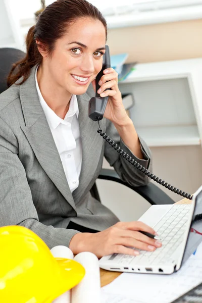 Uśmiechający się architekt kobiece rozmowy na telefon i za pomocą swojego laptopa i — Zdjęcie stockowe