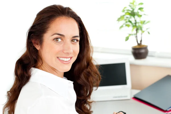 Сяюча бізнес-леді посміхається на камеру, сидячи в її офісі — стокове фото