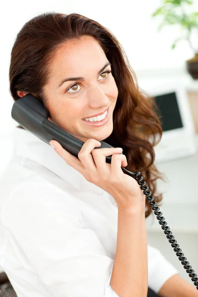 Attractive young businesswoman talking on phone sitting at her d — Stock Photo, Image