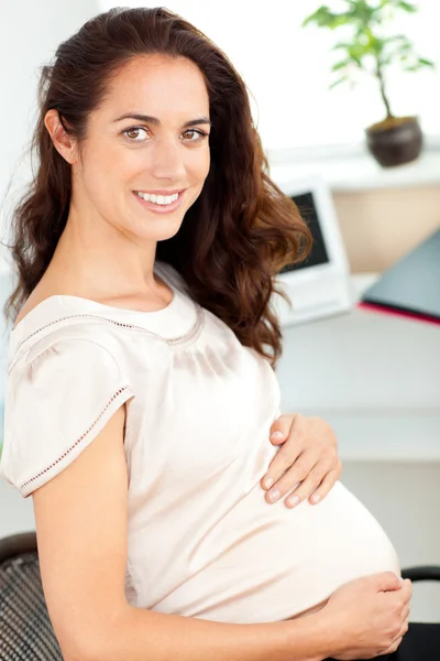 Embarazada mujer de negocios sonriendo a la cámara sentada en su escritorio —  Fotos de Stock