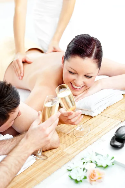 Amar pareja joven beber champán acostado en una mesa de masaje —  Fotos de Stock