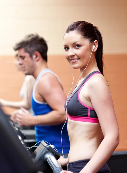 Cute athletic woman standing on a running machine with earphones — Stock Photo, Image