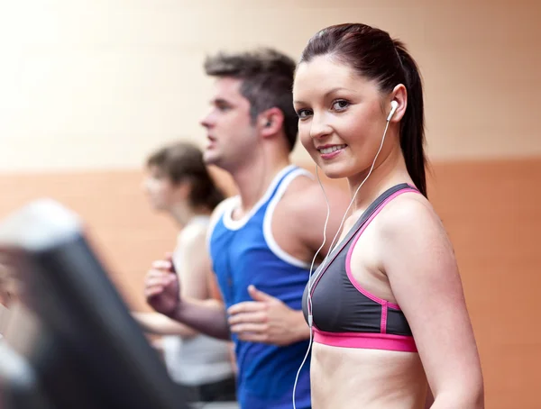 Young beautiful athletes with earphones exercising on a running — Stock Photo, Image