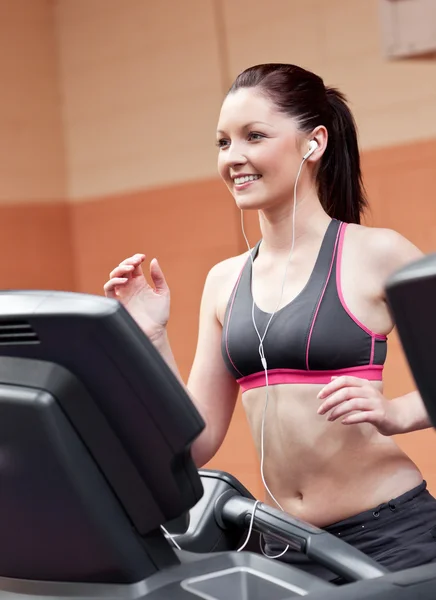 Mujer atlética sonriente entrenando en una máquina de correr con auriculares —  Fotos de Stock