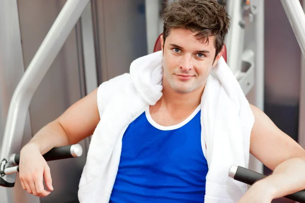 Confident young man with a towel using a bench press — Stock Photo, Image