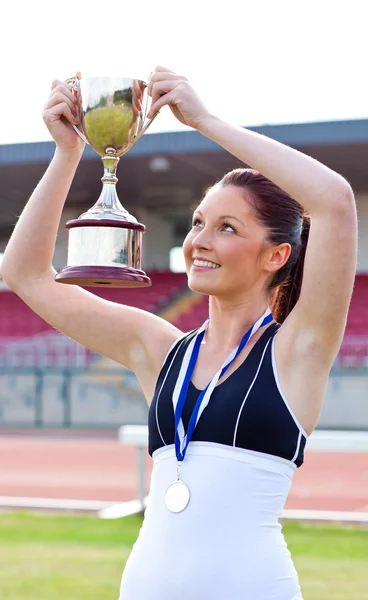 Joyful atleta feminina segurando um trofeu e uma medalha — Fotografia de Stock