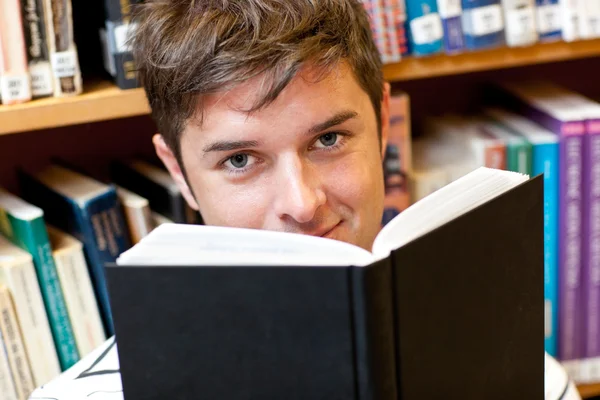 Porträt eines gut aussehenden männlichen Studenten, der im Sitzen ein Buch liest. — Stockfoto
