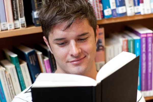 Πορτρέτο του ένα χαμογελαστό άνδρας των φοιτητών που διαβάζοντας ένα βιβλίο καθισμένος σε το — Φωτογραφία Αρχείου