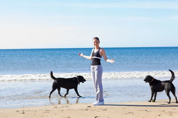 Jovem mulher esportiva cercada por dois cães — Fotografia de Stock
