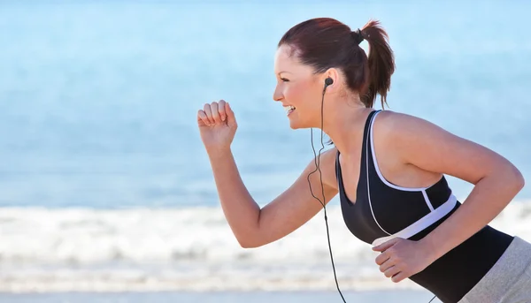 Primer plano de una mujer deportiva corriendo por la playa y escuchando música —  Fotos de Stock