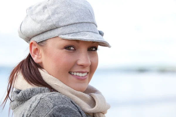 Portrait d'une jolie jeune femme avec bonnet et écharpe debout sur la plage — Photo