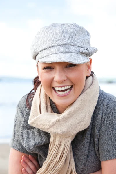 Śmiech kaukaski kobieta czapka i szalik stojąc na plaży — Zdjęcie stockowe