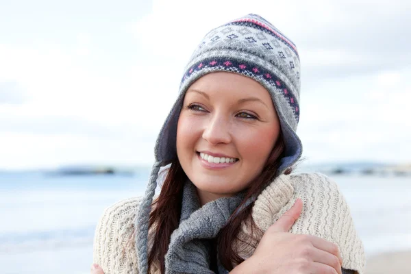Pretty woman with scarf and colorful hat standing on the beach — Stock Photo, Image