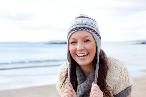 Mujer bonita con bufanda y sombrero de colores de pie en la playa —  Fotos de Stock
