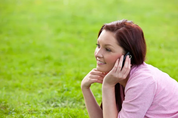 Encantada joven en el teléfono sentado en la hierba — Foto de Stock