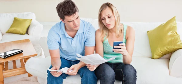 Concentrated young couple calculating bills sitting on the sofa — Stock Photo, Image