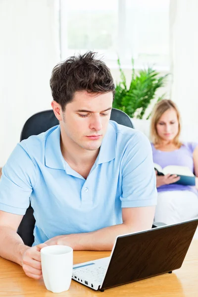 Concentrated man working on his laptop with his girlfriend readi — Stock Photo, Image