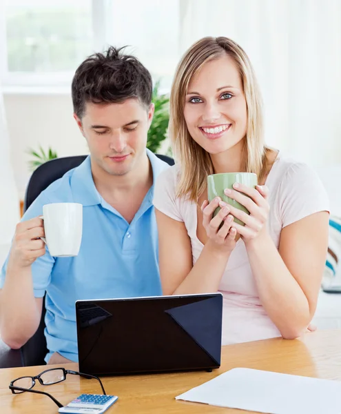 Young couple drinking coffee and working together on the laptop — Stock Photo, Image
