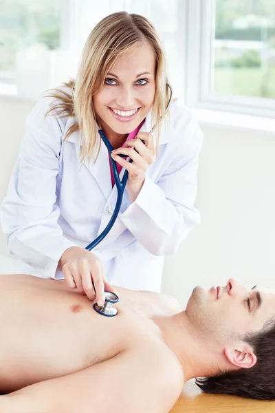 Bella medico femminile utilizzando stetoscopio su un paziente — Foto Stock