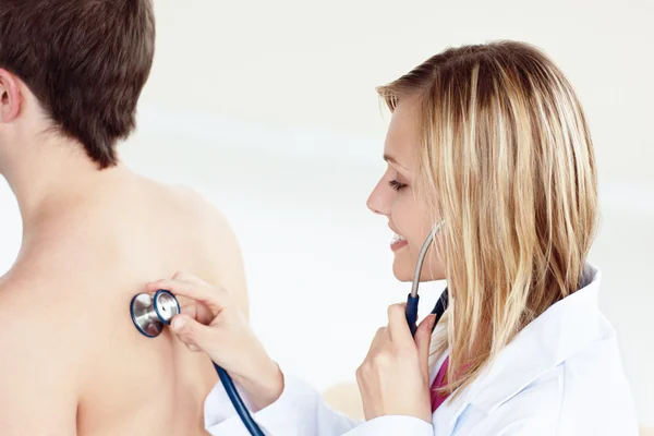 Aantrekkelijke vrouwelijke arts met behulp van stethoscoop op haar patiënt is terug — Stockfoto