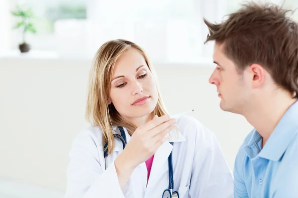 Concentrated female doctor looking at patient's temperature — Stock Photo, Image