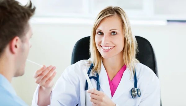 Attractive female doctor taking patient's temperature in her off — Stock Photo, Image
