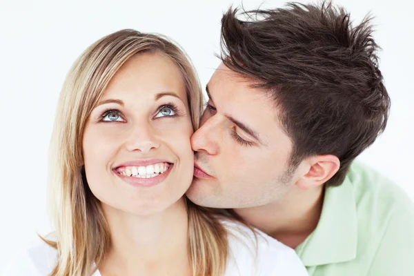 Ostrożny człowiek całując jego dziewczyna uśmiechający się przeciwko biały backg — Zdjęcie stockowe
