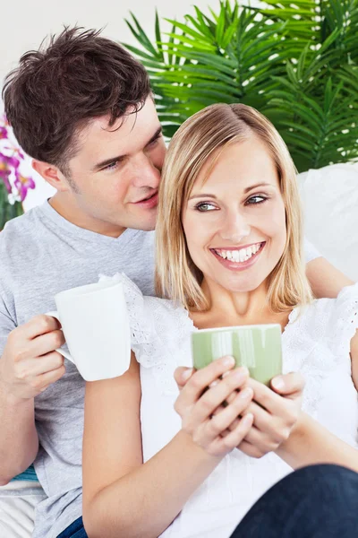Schöner Mann flüstert seiner Freundin etwas zu, während er trinkt — Stockfoto