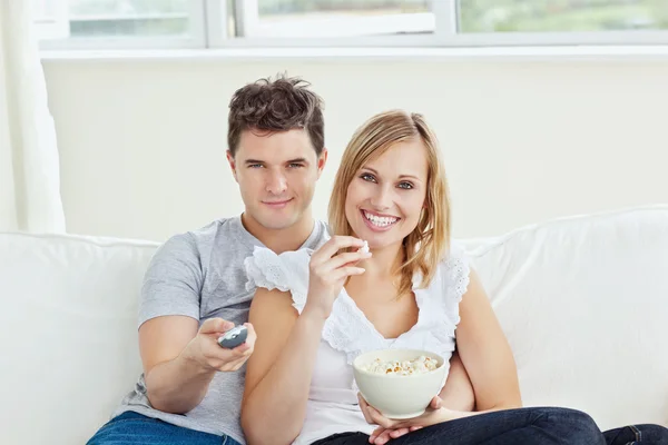 Χαμογελώντας νεαρό ζευγάρι ψάχνει στην τηλεόραση — Φωτογραφία Αρχείου