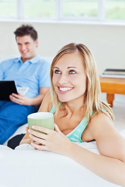 Jeune couple. femme boire du thé lorsque l'homme en utilisant un ordinateur portable — Photo