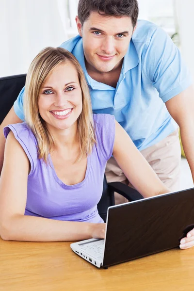 Leende par använder dator på skrivbordet — Stockfoto