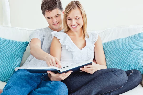 Όμορφο ζευγάρι ερωτευμένων, διαβάζοντας ένα βιβλίο στον καναπέ — Φωτογραφία Αρχείου