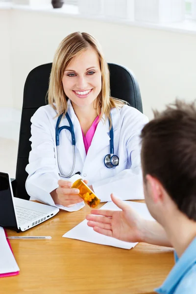 Lachende arts givng pillen om haar patiënt — Stockfoto