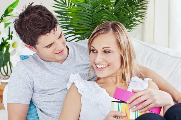 Beautiful couple lying on the sofa with a present — Stock Photo, Image