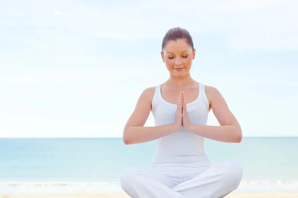Koncentrerad kvinna utövar yoga på stranden — Stockfoto
