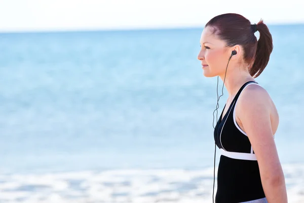 Junge Frau hört Musik am Strand — Stockfoto