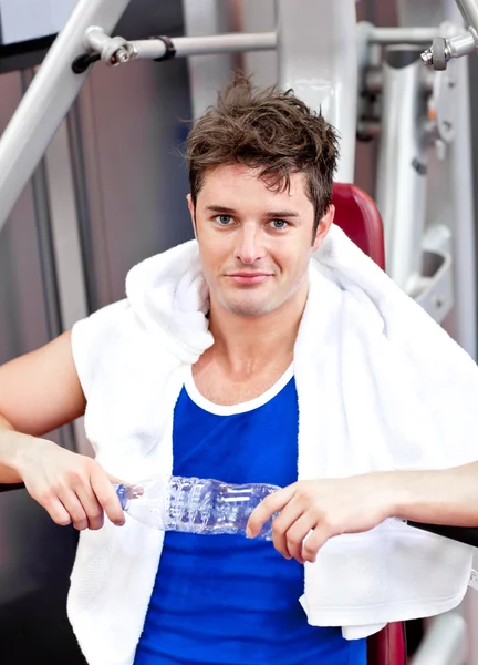 Handsome man sitting on a bench press after exercises — Stock Photo, Image