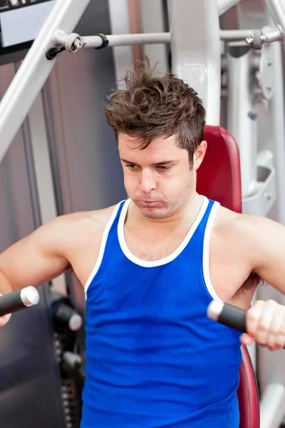 Young man putting a lot of effort sitting on a bench press — Stock Photo, Image