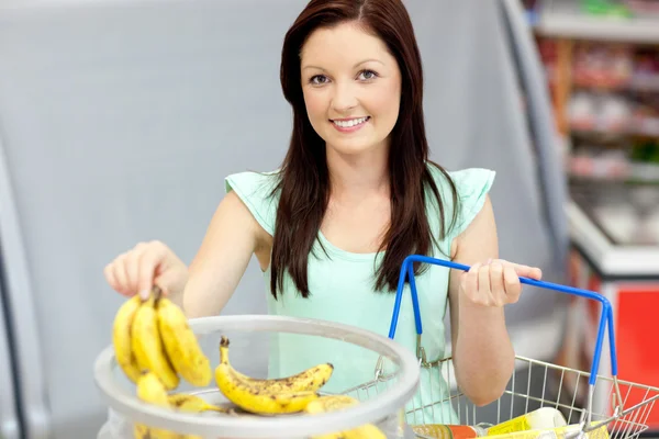 Mulher saudável com cesta de compras comprando bananas em um supermercado s — Fotografia de Stock