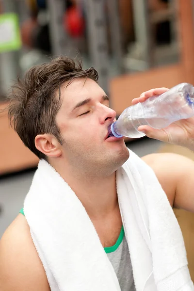 Измученный человек пьет воду с полотенцем вокруг шеи после — стоковое фото