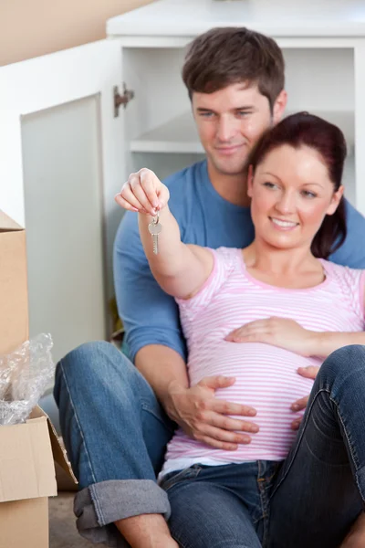 Portrait of future parents looking at key sitting on the floor — Stock Photo, Image