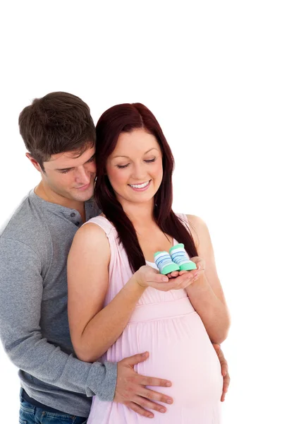 Young future parents looking at baby shoes against a white backg — Stock Photo, Image