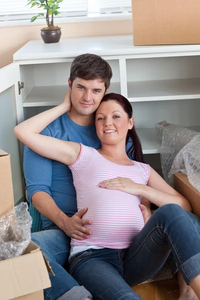 Šťastný pár v jejich nový domov, která sedí na podlaze mezi cardbo — Stock fotografie