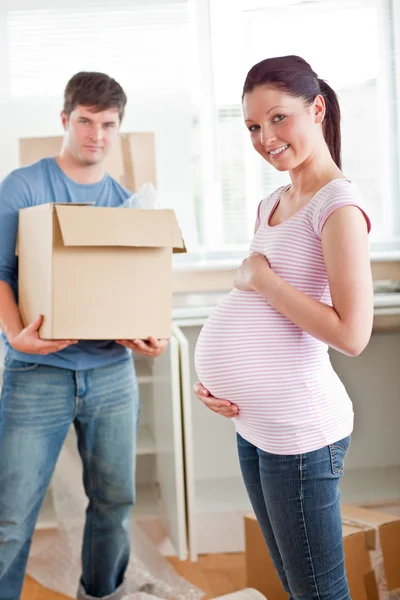 Очаровательная беременная женщина с мужем, держащим картон в ки — стоковое фото