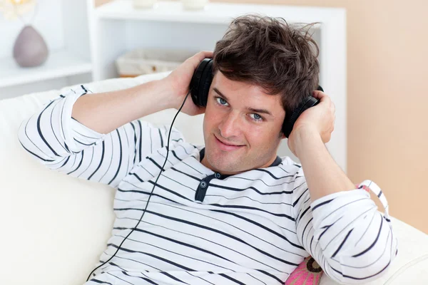 Legrační člověk poslech hudby se sluchátky na posezení v jeho livi — Stock fotografie