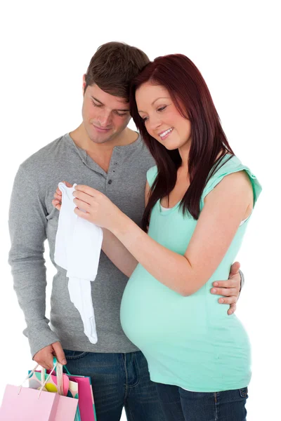 Futuro mãe e pai com sacos de compras olhando para roupas de bebê — Fotografia de Stock