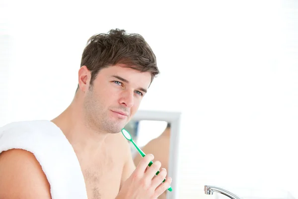 Esperto jovem macho escovando seu dente com toalha em seu ombro — Fotografia de Stock