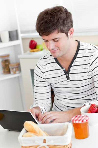 Gorgeous man working on his laptop during breakfast — Stock Photo, Image
