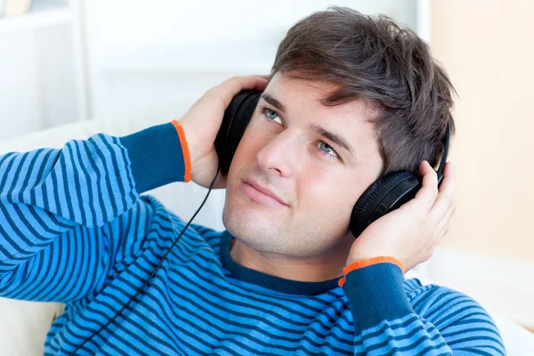 Attraktiv ung man lyssnar musik sitter i vardagsrummet — Stockfoto