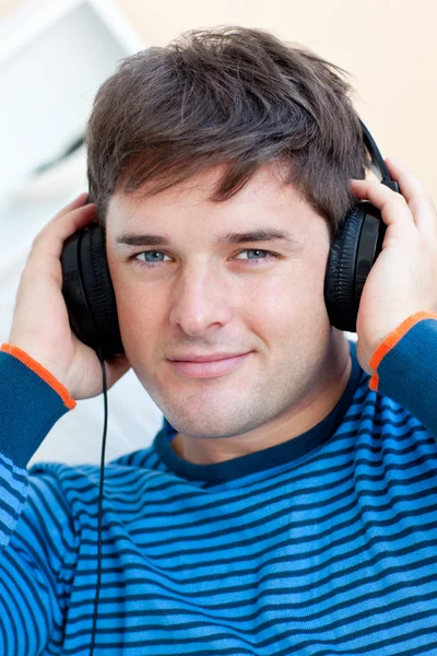 Mírumilovný člověk poslech hudby pomocí sluchátek se usmívá na cam — Stock fotografie